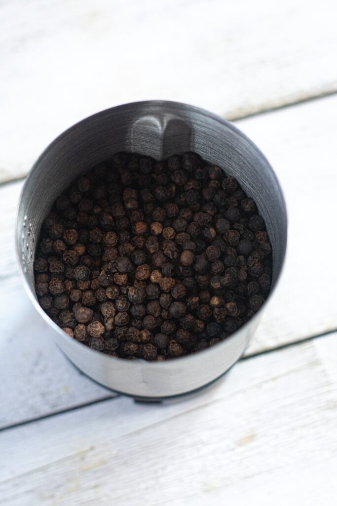 whole black peppercorns in a spice grinder