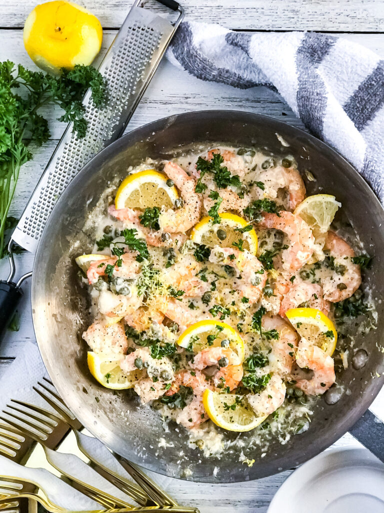 Creamy Shrimp Piccata | Keto, Low-Carb in a skillet on a white background with gold forks, parsley, and a microplane grater.