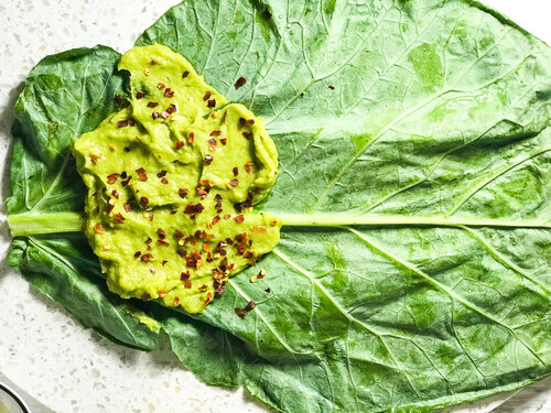 avocado spread and crushed red pepper flakes on a collard green leaf
