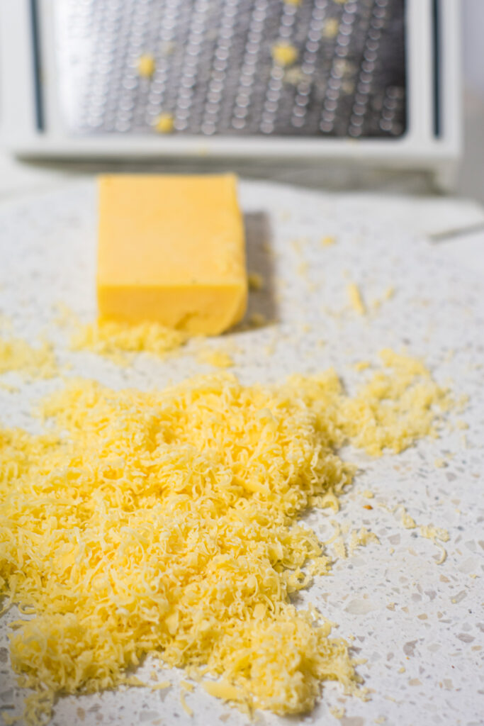 Grated Gouda on a White Cutting Board