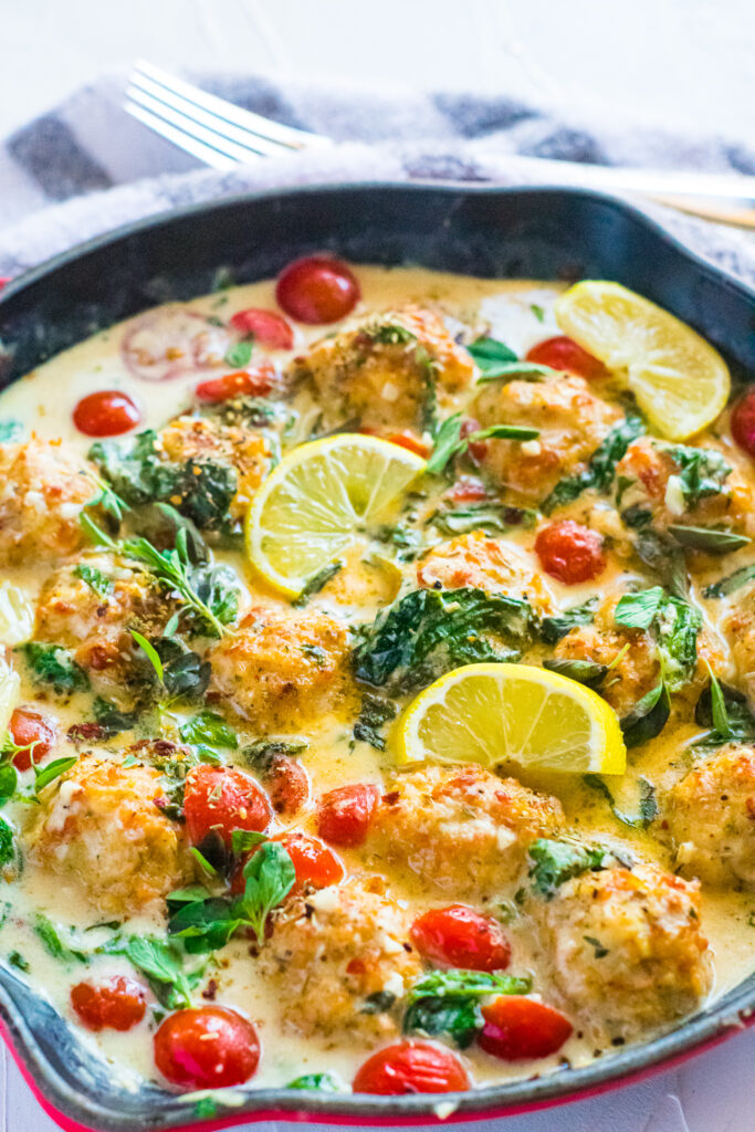 Creamy Tuscan Chicken Meatballs in a pan with napkin and fork