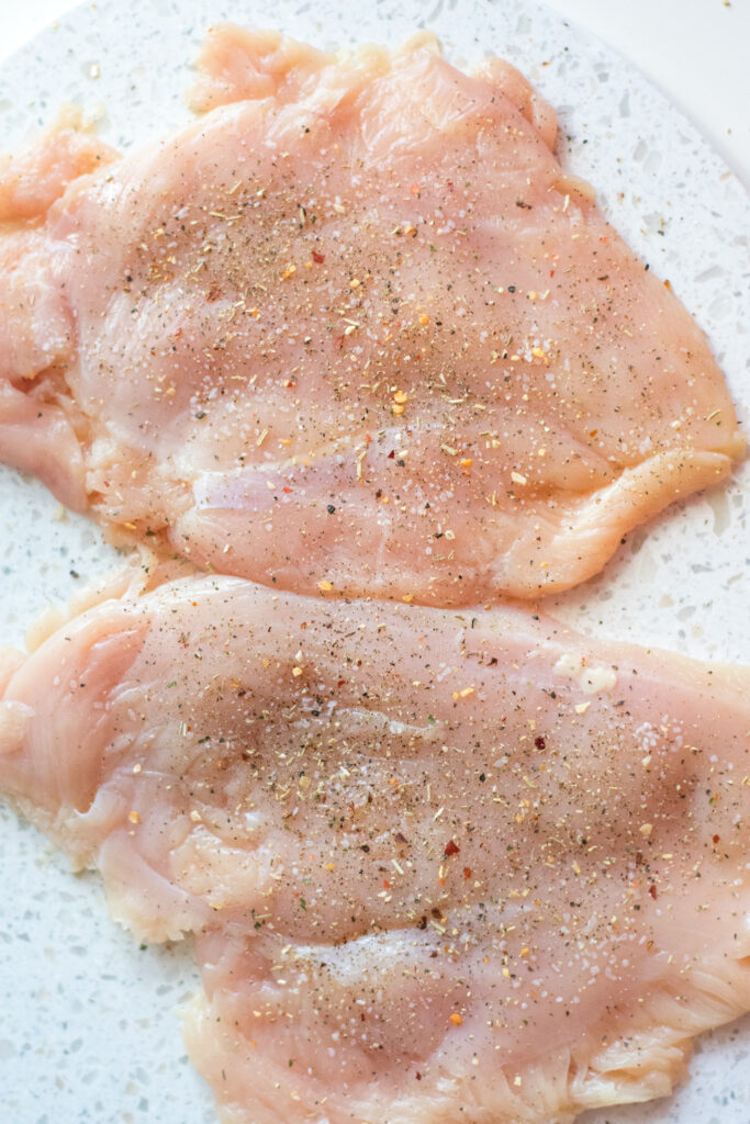 flattened chicken breasts - seasoned- on cutting board