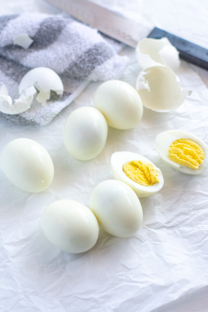 peeled, hard-boiled eggs sitting on white parchment paper