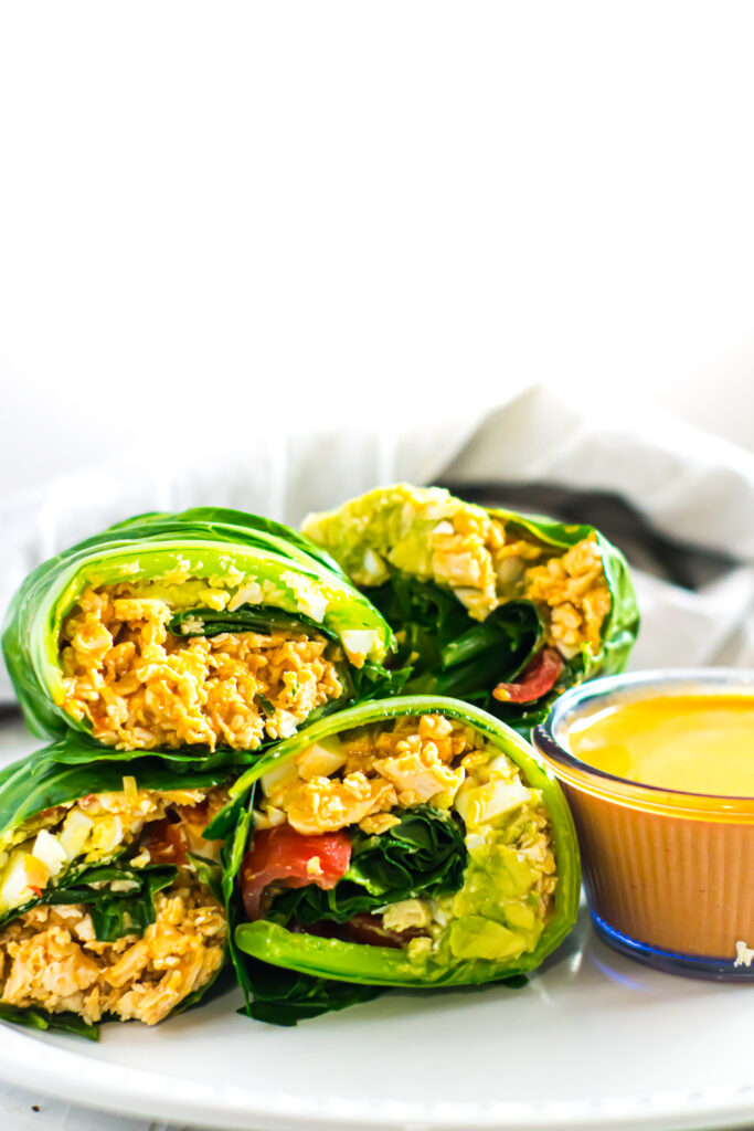 Buffalo chicken collard green wraps on a white plate with white background. 