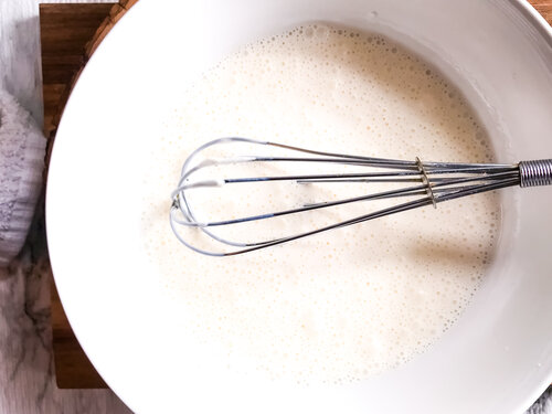 Whisk in a white bowl of buttermilk used to make blackened ranch dressing