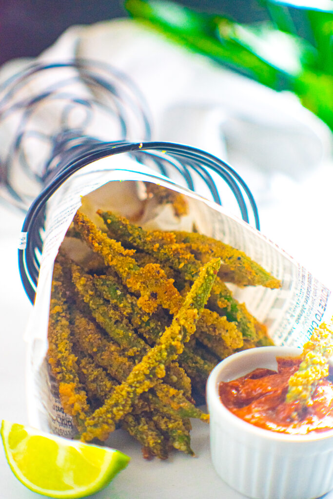 Parmesan crusted green bean fries in a fry cone with limes and dipping sauce.