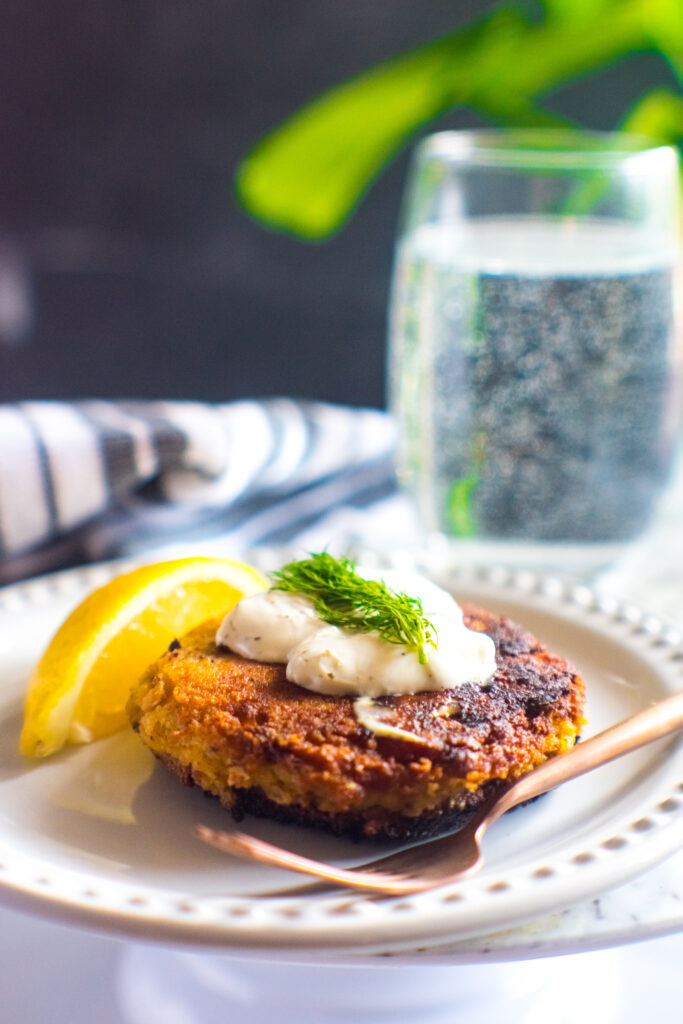 Keto salmon croquettes on white plate with tartar sauce, lemon and dill.
