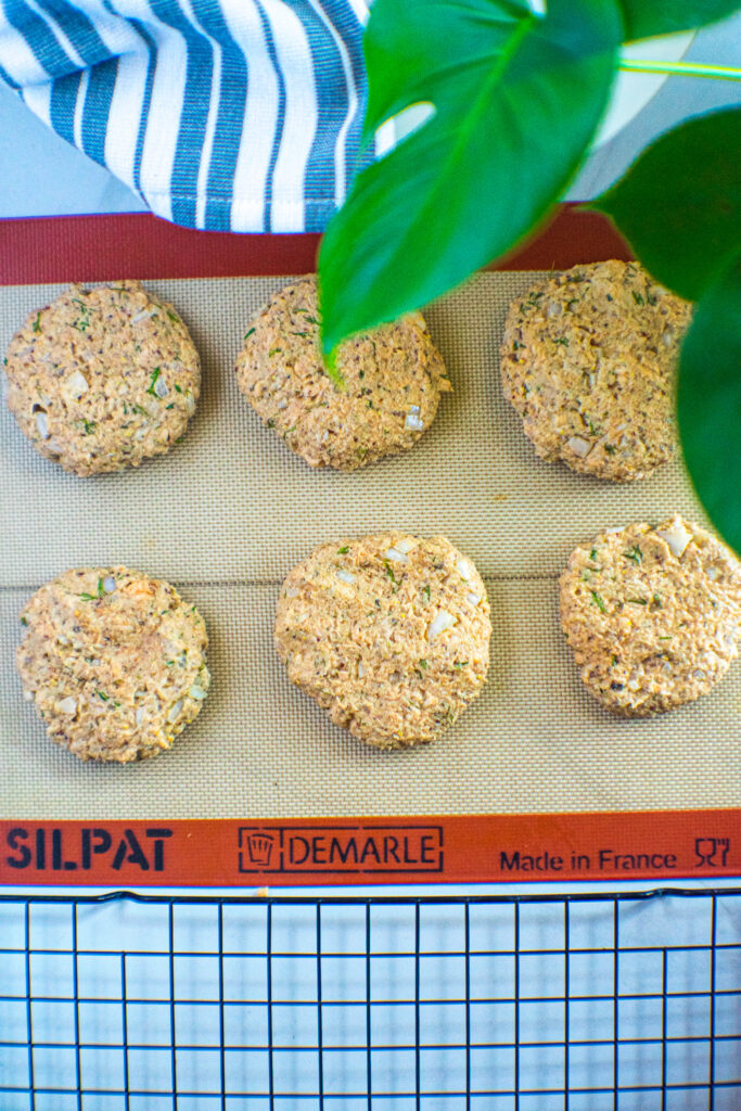 Uncooked salmon croquette patties on a silicon baking sheet.