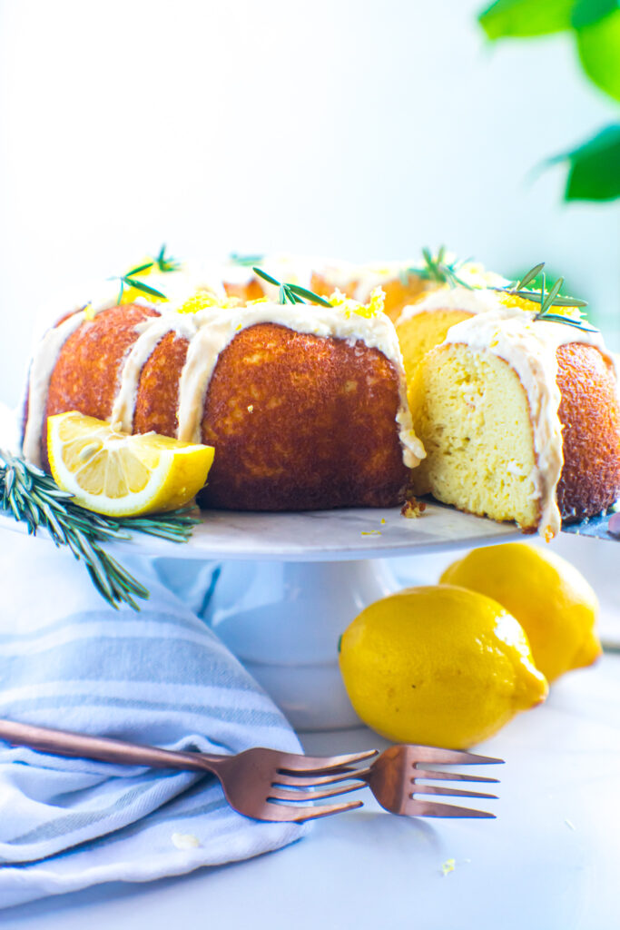 keto-friendly rosemary lemon pound cake sliced on a white cake stand.