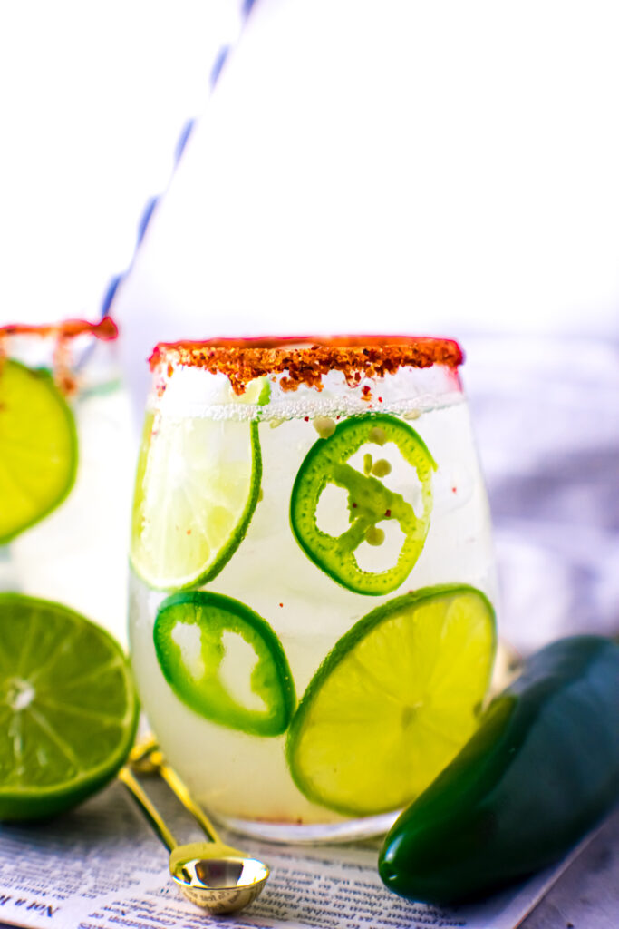 Jalapeño margarita in clear glass with rimmed with tajin. 