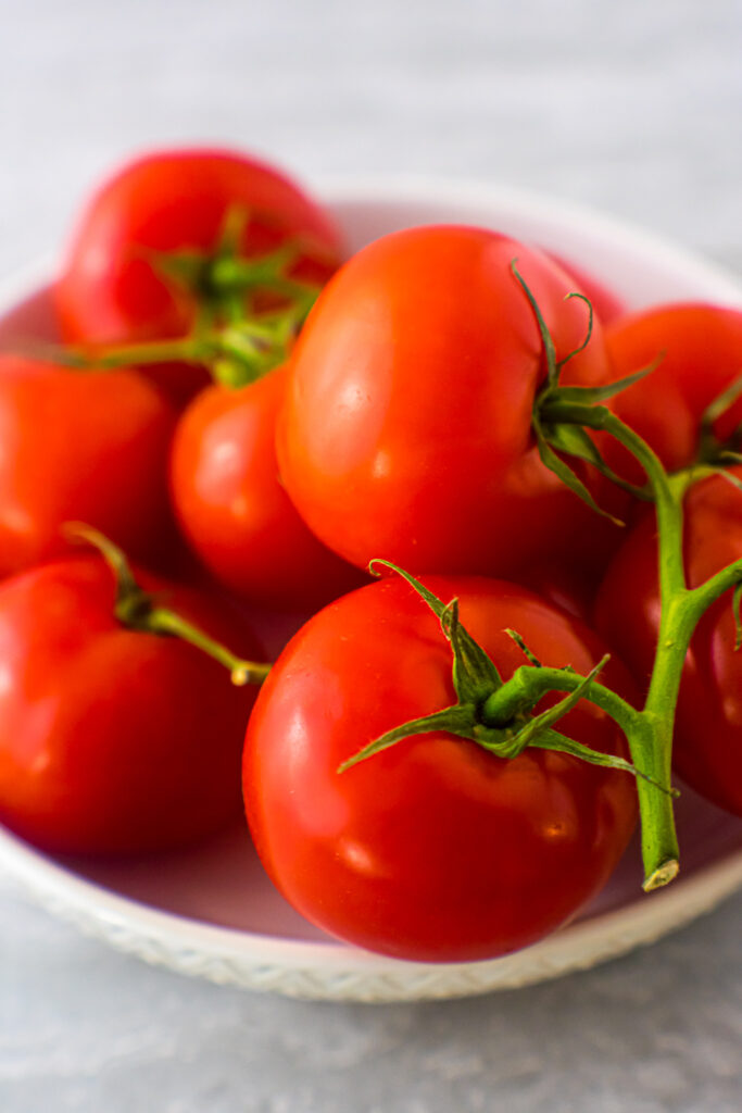 Vine-ripened tomatoes in a white bowl.