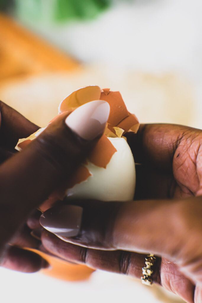 Close up shot of brown hands peeling an egg