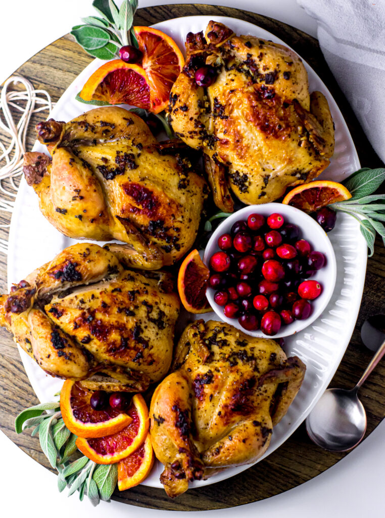 Sage Rubbed Cornish Hens with Blood Orange on a white serving platter.