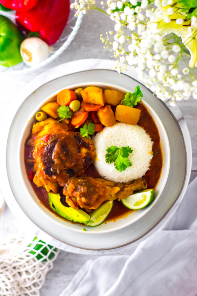 Pollo Guisado (chicken stew) served with white rice in a white bowl. 
