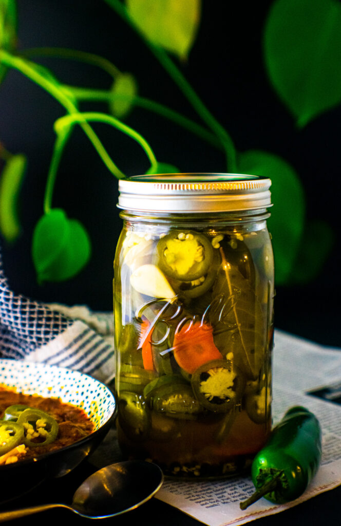 Pickled jalapeños, carrot, and garlic in a glass mason jar.